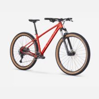 Red mountain bike with black front suspension, tan tires, and a side view on a white background.