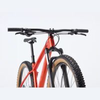 Front view of a red mountain bike with knobby tires and a black front suspension fork.