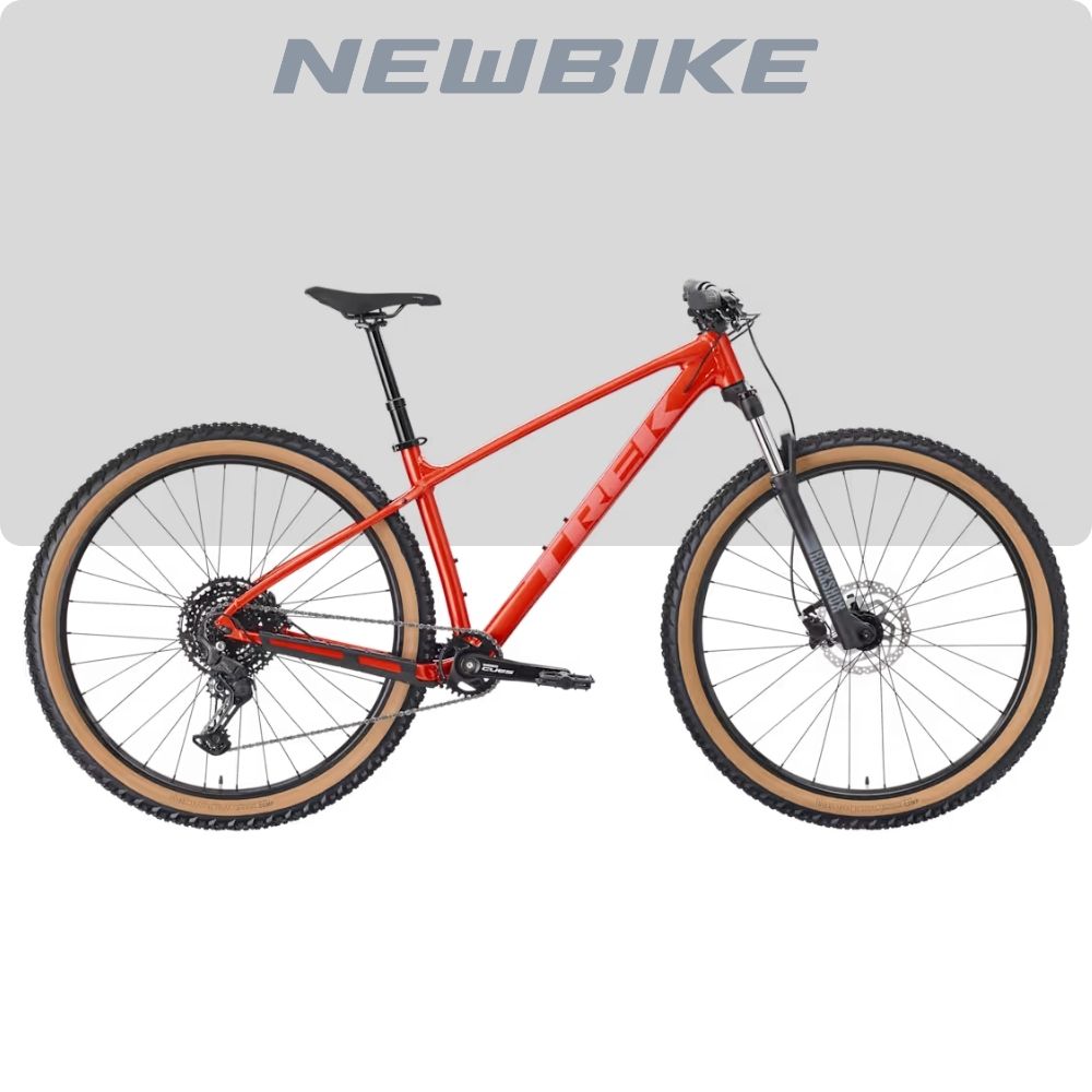 Red hardtail mountain bike with tan-wall tires and front suspension, shown in profile against a light gray backdrop.