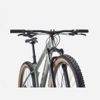 Front view of a green hardtail mountain bike with knobby tires, flat handlebars, and a suspension fork.
