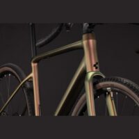 Close-up of a gradient-colored bicycle frame and front fork against a dark background, showing a modern textured finish.