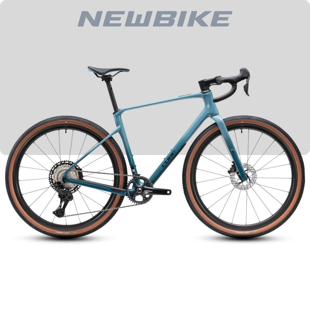 Blue gravel bike with drop handlebars, tan-wall tires, and disc brakes shown in profile. Teal frame with multiple gears visible.