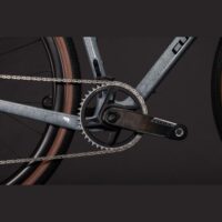 Close-up of a bicycle crankset and chainring on a metallic frame, with a silver chain and prominent Force-branded crank arm.